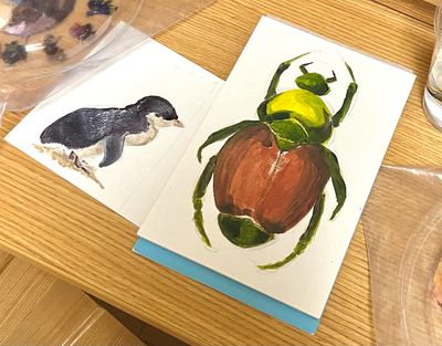 Painting of a penguin and a large green and red bug